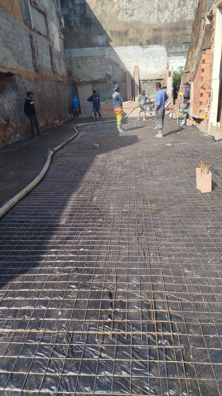 Instalação de armadura metálica (tela de aço) sobre lona para concretagem de laje