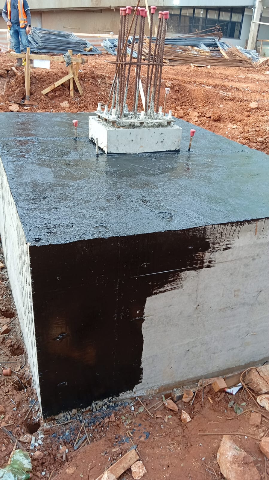 Bloco de coroamento recém-concretado com armaduras e esperas em obra de fundação